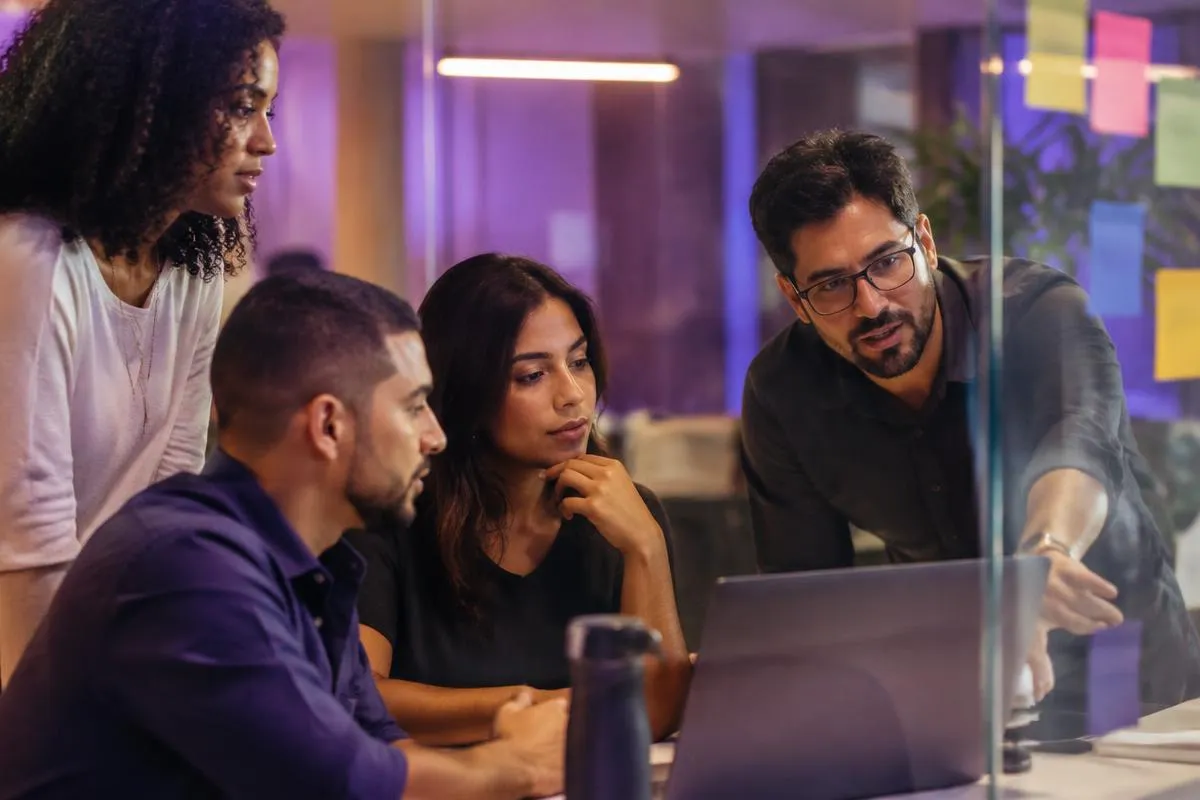 Equipe de operação reunida diante de painéis de indicadores em um escritório de e-commerce.